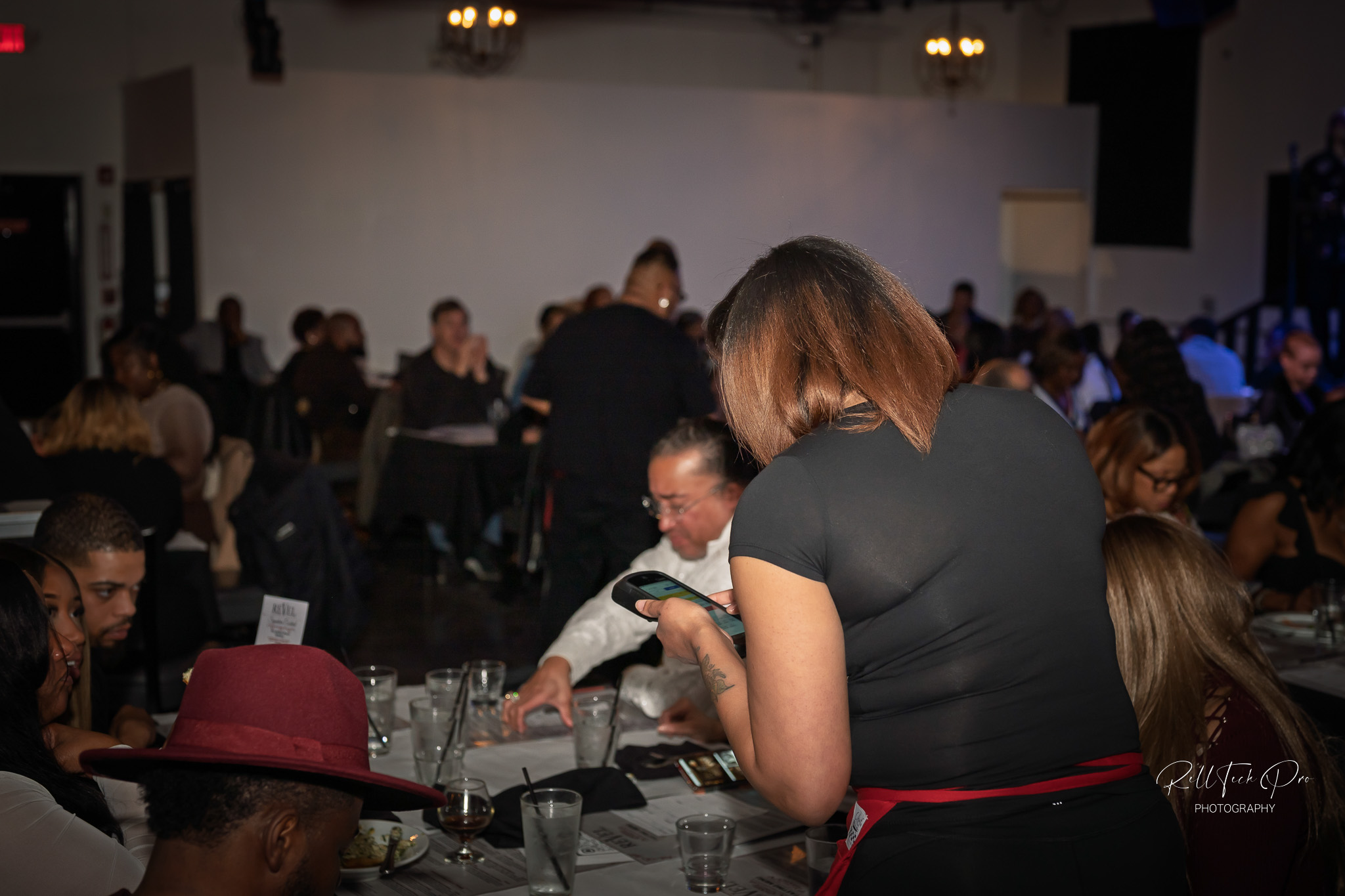 A server takes an order, while guests socialize and enjoy the vibrant atmosphere and live entertainment.