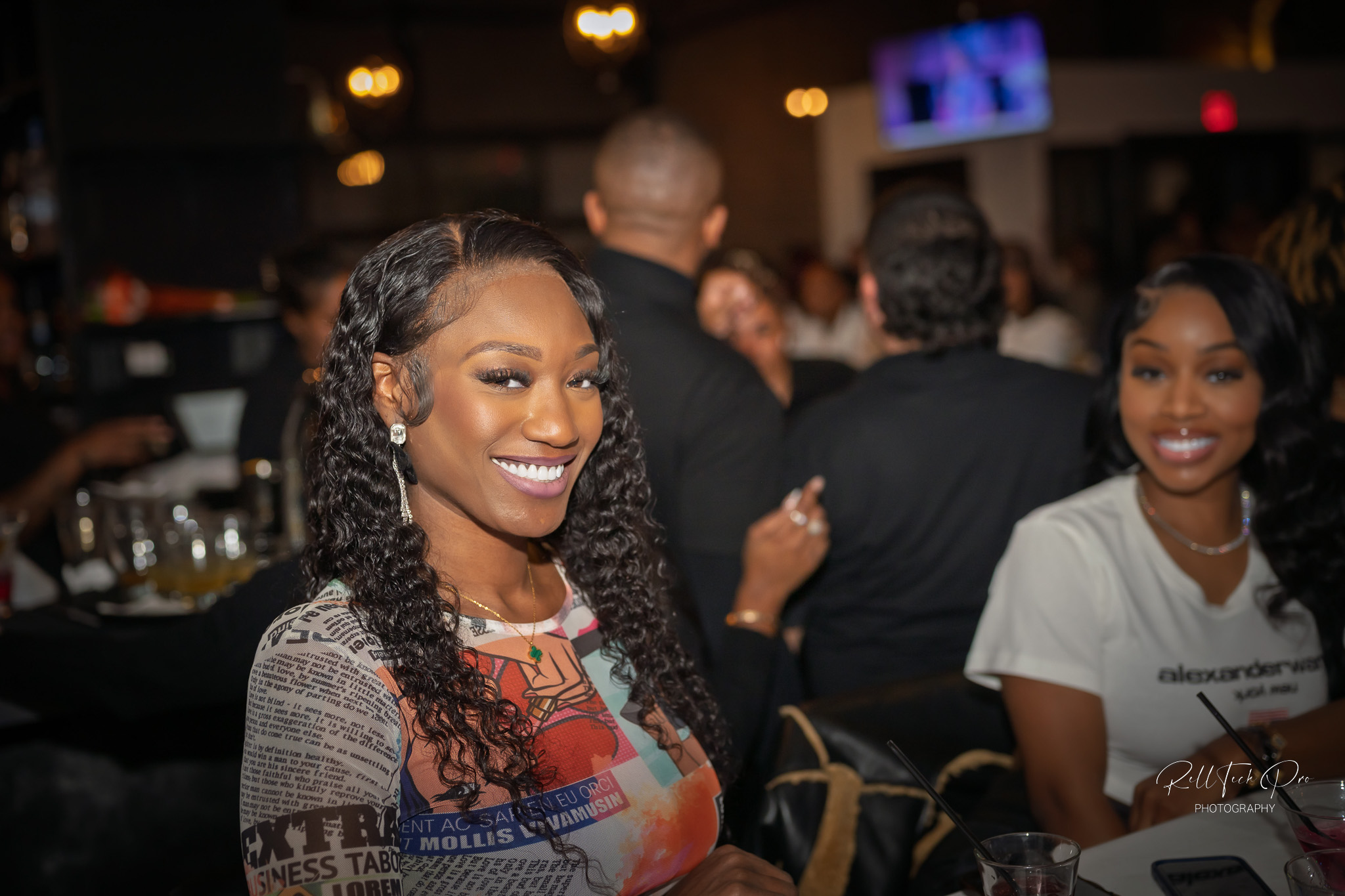 Two smiling women enjoying their time at a lively social event at Revel Supper Club.